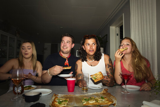 Group of friends having pizza during dinner party at home