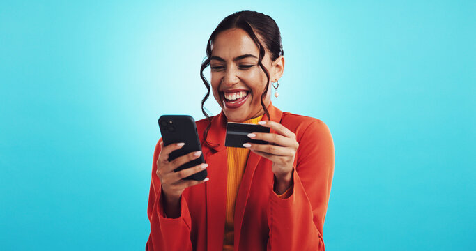 Happy woman, phone and credit card in studio for success, lottery winner and excited for victory. Blue background, online and wow for competition achievement, bonus income and discount reward on app