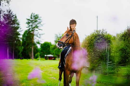 Smiling woman wearing helmet and sitting on horse