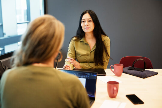 Manager taking interview of candidate while sitting at desk in office