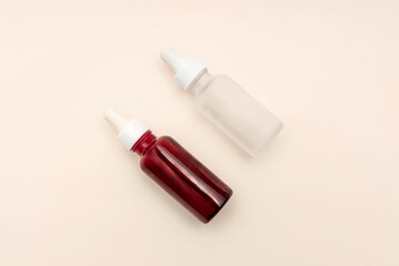 Two Essential oil or serum dropper bottles resting on beige surface, wellness and skincare