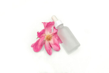 Rose serum or essential oil in glass bottle with dropper lying on white background