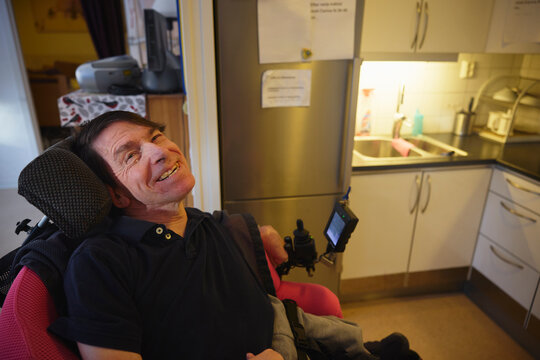 High angle view of smiling mature man with cerebral palsy sitting on wheelchair