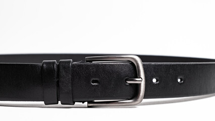 Black Classical leather Belt isolated on white background close-up. Fastened fashionable unisex accessory with dark chrome matted metal buckle. Man lux strap. Haberdashery goods. Minimalistic style.