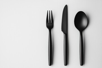 Elegant black cutlery set including a fork, knife, and spoon arranged on a clean white surface, showcasing modern minimalist design and a sleek, sophisticated aesthetic.