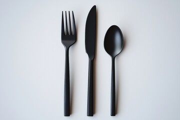 Minimalist black cutlery set on a clean white backdrop, featuring a fork, knife, and spoon, conveying modern elegance and a sophisticated dining aesthetic.