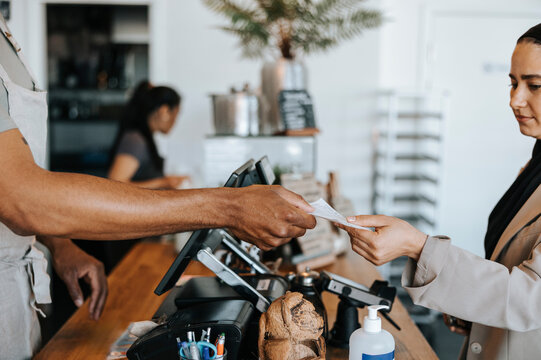 Male barista giving bill to customer at checkout