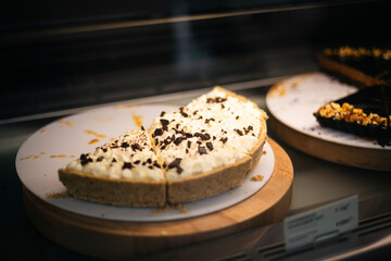 Banana caramel cake with cream on display in a pastry shop window.