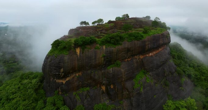 Sigiriya Steep Rock Fortress With Vegetation And Sunrise Fog In Matale District, Sri Lanka. drone ascend
