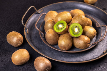 Fresh kiwi fruits displayed on a dark metal tray