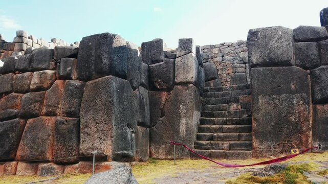 Pan right reveals massive stone fortress wall at Sacsayhuam&aacute;n ruins, Cusco, Peru