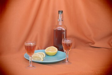 still life with bottle and two glasses  with homemade tincture with lemon 