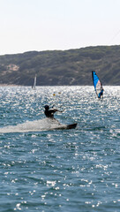 Silhouette of a kitesurfer gliding at high speed over the waves, leaving behind a trail of water...