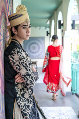 Vertical young wealthy handsome Indian man in traditional India costume standing in luxury room