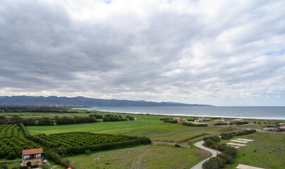 Obraz premium Breathtaking coastal landscape with lush farmland and distant mountains near the serene sea