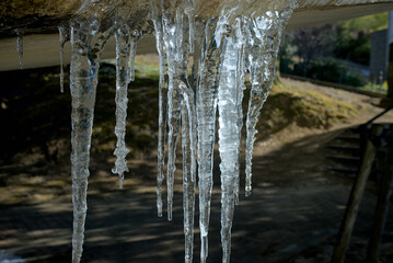  冬の陽光に輝く橋の下の氷柱