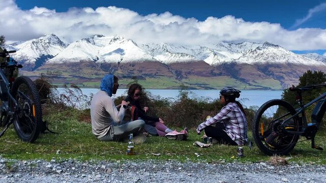 Bikers taking a break at a scenic viewpoint overlooking Lake Wakatipu and Mount Larkins