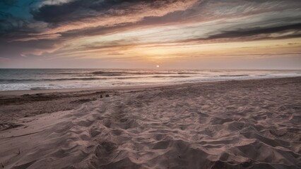 Fototapeta premium Tranquil beach at sunset with soft sand in the foreground and calm sea under a colorful sky, horizon blending with vibrant clouds.