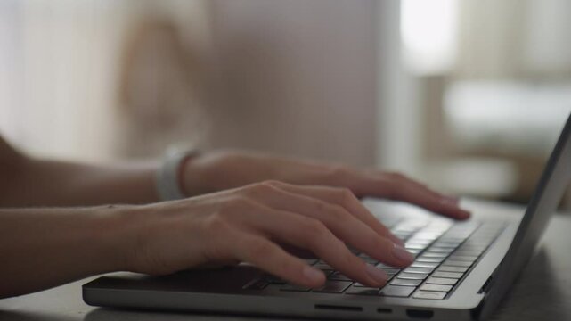 Close-up of hands typing on a laptop keyboard