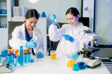 Fototapeta premium Two Asian female scientists in a high-tech lab analyzing biochemical samples, using micro pipettes,
