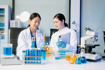Fototapeta premium Two Asian female scientists conduct biochemical research using micro pipettes in a high-tech medical lab