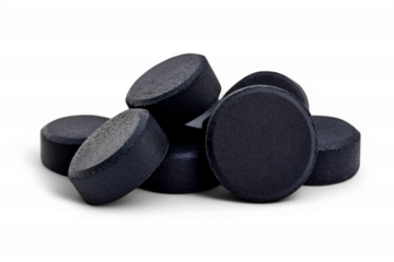 Black charcoal soap disks arranged on black surface