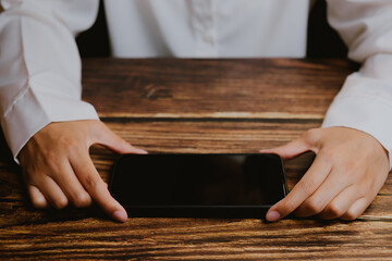 Hands Holding Smartphone on Wooden Table Background, Focused View