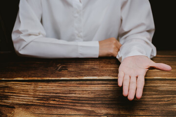 Hand Gesture on Wooden Table with White Shirt in Dark Environment