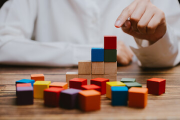 Colorful Building Blocks Stacked on Wooden Table by Child's Hand