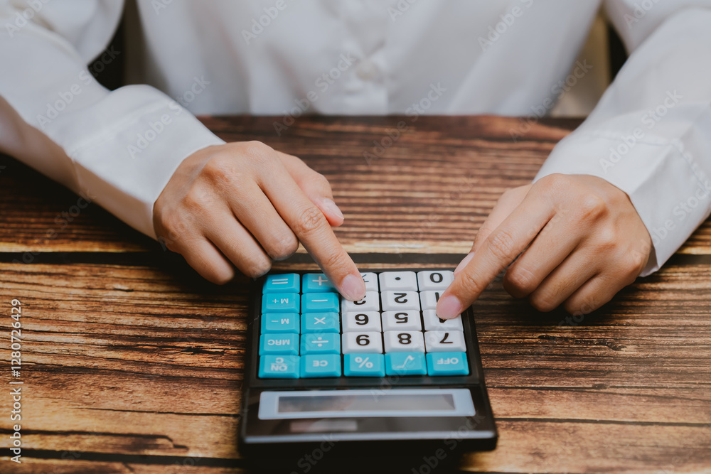 Poster close-up view of hands using calculator on wooden table surface