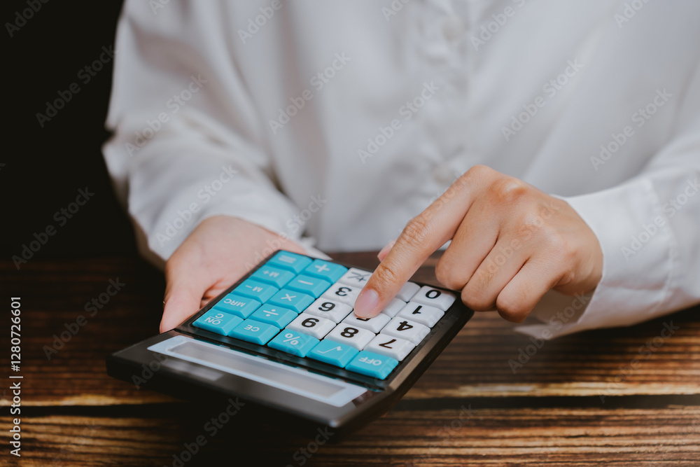 Poster hand using large button calculator on wooden table surface