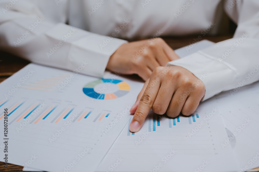 Poster businessperson analyzing charts and data with a pen on a table