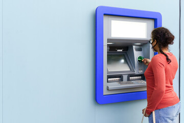 Black woman wearing protective mask while withdrawing money at ATM.