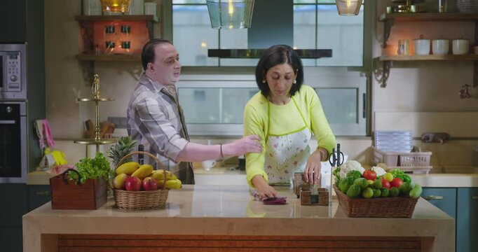 Indian upset middle aged adult gen x couple pair male female do bad fight argue indoor modern kitchen home. older angry husband man slap abuse insult each other shout on lady wife show knife at house