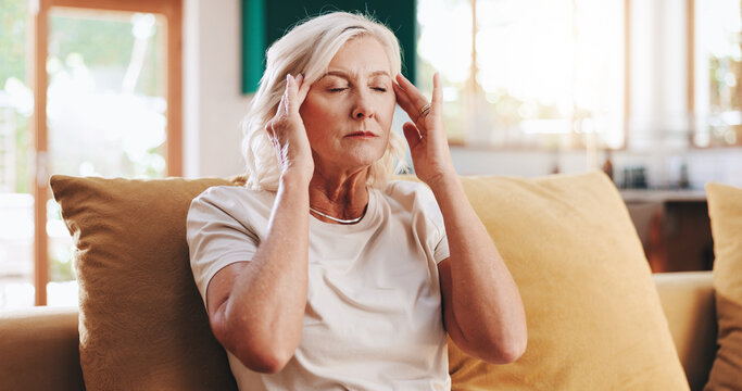 Headache, massage and stress with senior woman on sofa in living room of apartment for pain relief. Burnout, migraine and temple with old person in retirement home for health, rest or wellness