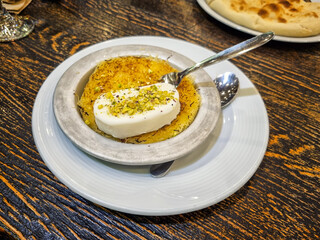 Delicious traditional Turkish dessert, Kunefe made with shredded filo pastry, honey, pistachios and white ice cream