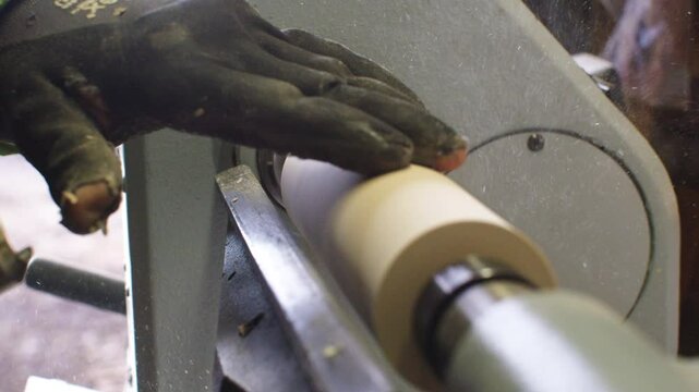 A skilled artisan operates a lathe to shape a piece of wood, demonstrating craftsmanship and attention to detail in a rustic woodworking workshop.