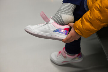 Close-up of a child putting on stylish white and pink velcro sneakers, getting ready for the day