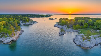 Obraz premium Aerial view of a serene sunset over a lake with islands and bays, surrounded by lush forests and small rocky isles, captured in the summer from a drone perspective.