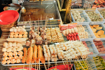 An assortment of various Korean street snacks neatly arranged in trays, showcasing a colorful and appetizing display of popular treats