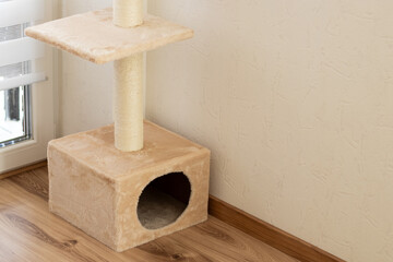 A beige cozy cat tree house without a cat standing in living room at home