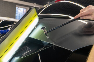 Removing dents on the car. PDR technology. Car body repair without painting. A specialist repairs a dent on the car body without painting. Body car repair.