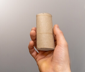Man's hand taking an empty toilet paper in a WC. Empty toilet paper roll in hand. Man's hand holding brown paper tube close-up. 