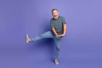 Happy senior man with grey beard striking a playful pose against a vibrant purple background