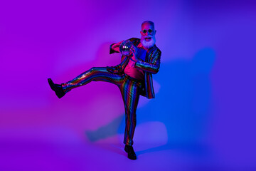 Obraz premium Full length photo of cool carefree mature guy dressed glamour costume star eyewear dancing disco emtpy space isolated neon purple color background