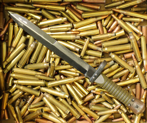 military bayonet with ammo in the background and selective focus