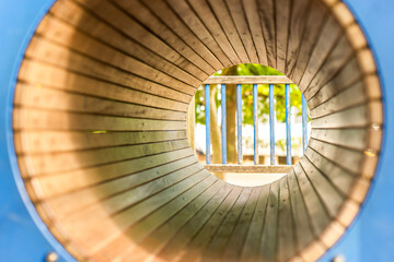 View through the wooden tube on playground without people in sunny day. Mockup or podium for designers