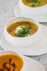 Delicious bowls of soup with fresh herbs, served on elegant white plates. The warm colors and textures invite a comforting dining experience