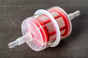 Transparent automotive fine fuel filter on a gray background, close-up