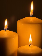 Three candles, flame, light, warmth, dark background.